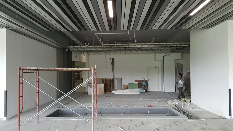 Grand plateau intérieur en chantier, sol brut, échafaudage roulant et murs blancs